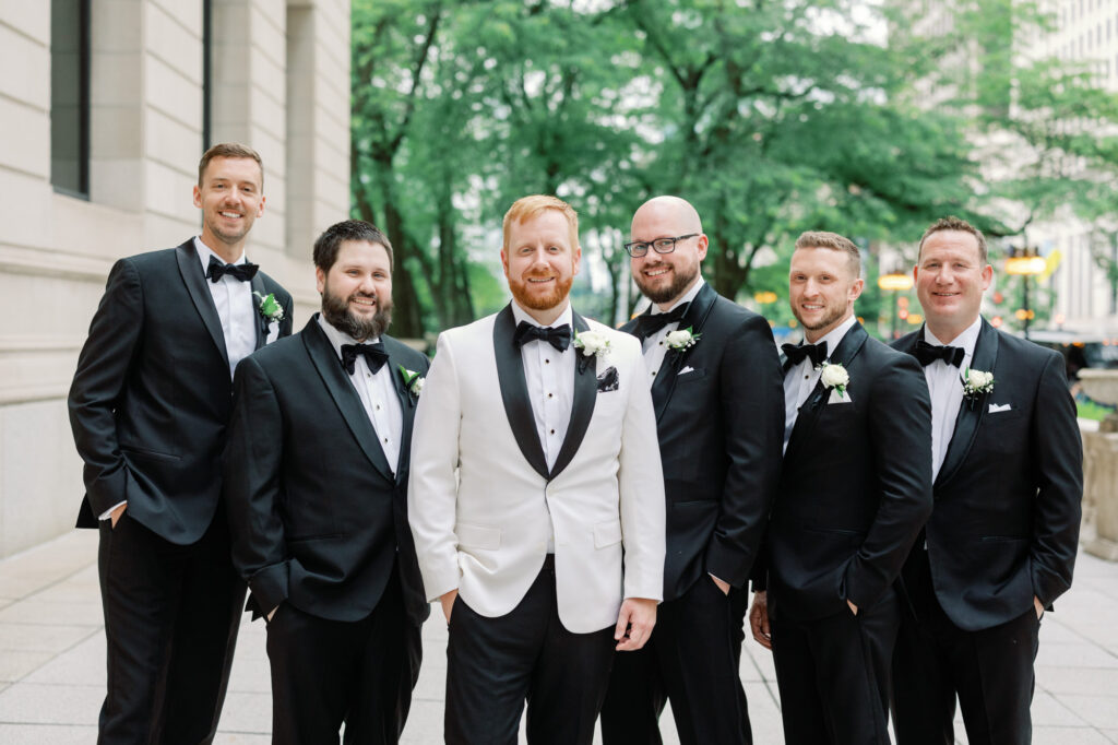 Groom and groomsmen standing together in black tuxedos during wedding portraits in Chicago.