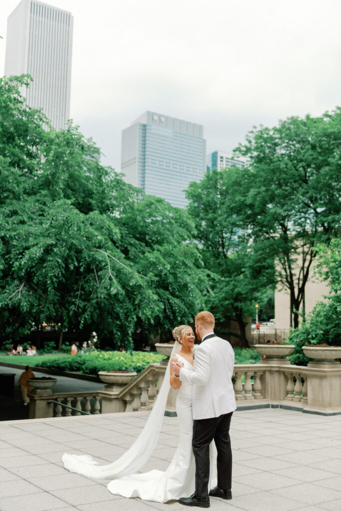 Bride and groom embracing with Chicago skyline visible during wedding portraits near the Art Institute.