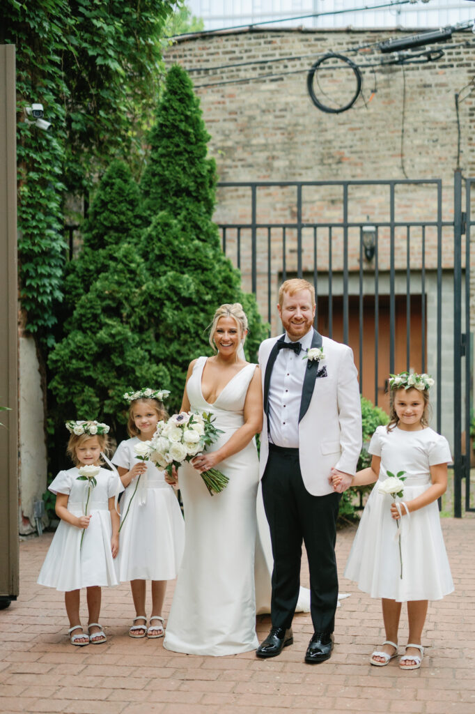 Bride and groom standing with flower girls outside Mae District before the ceremony.