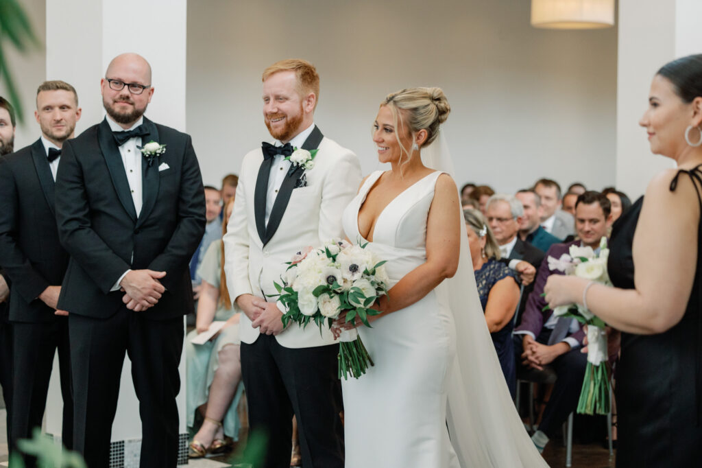 Bride and groom holding hands and smiling during their ceremony at Mae District.