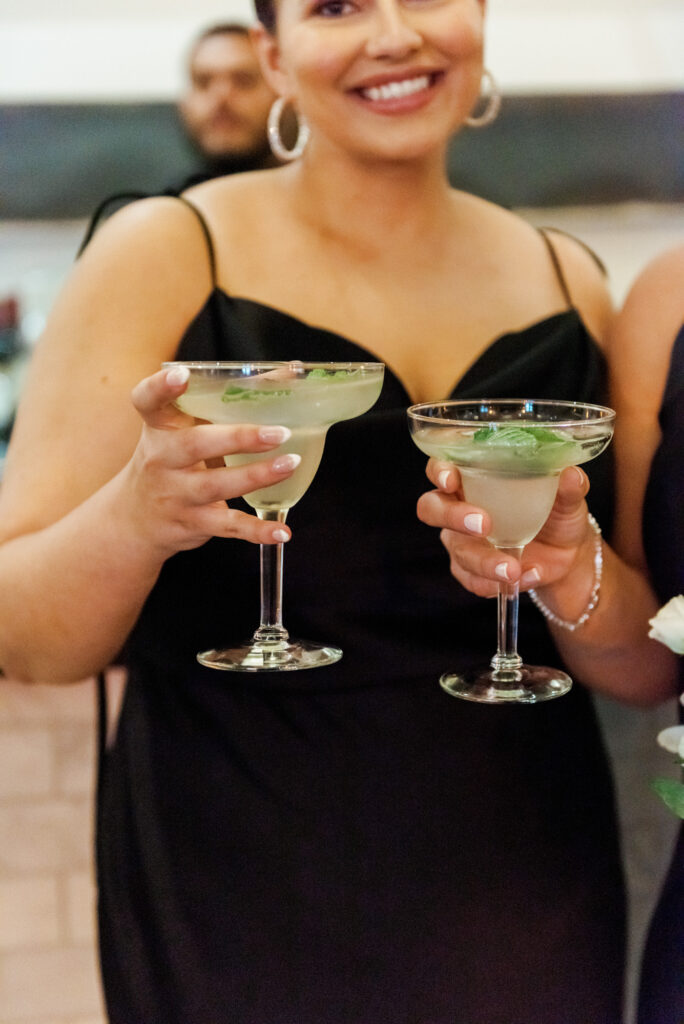 Guest holding cocktails and smiling during cocktail hour at Mae District Chicago.