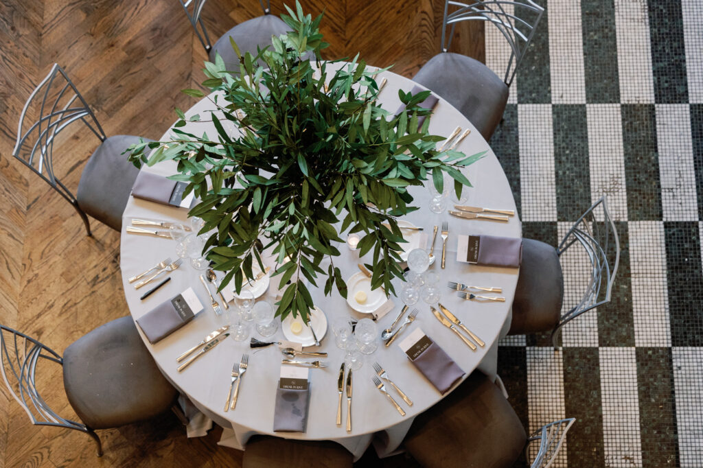 Round reception table with greenery centerpiece styled at Mae District Chicago venue.