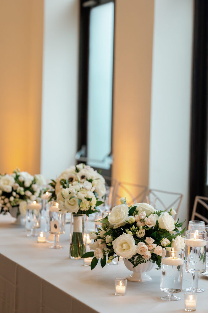 Reception space with floral centerpieces and candlelight at Mae District wedding.