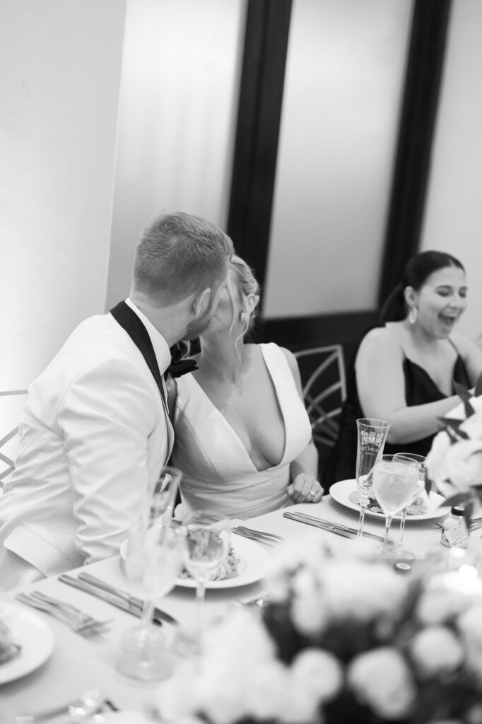 The bride and groom sharing a quiet moment and smiling at each other during dinner at their Mae District Chicago wedding.