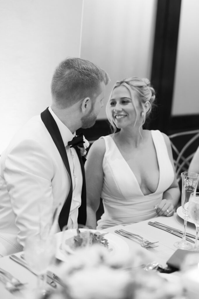 Black and white photo of the couple laughing together at their reception at Mae District in Chicago.