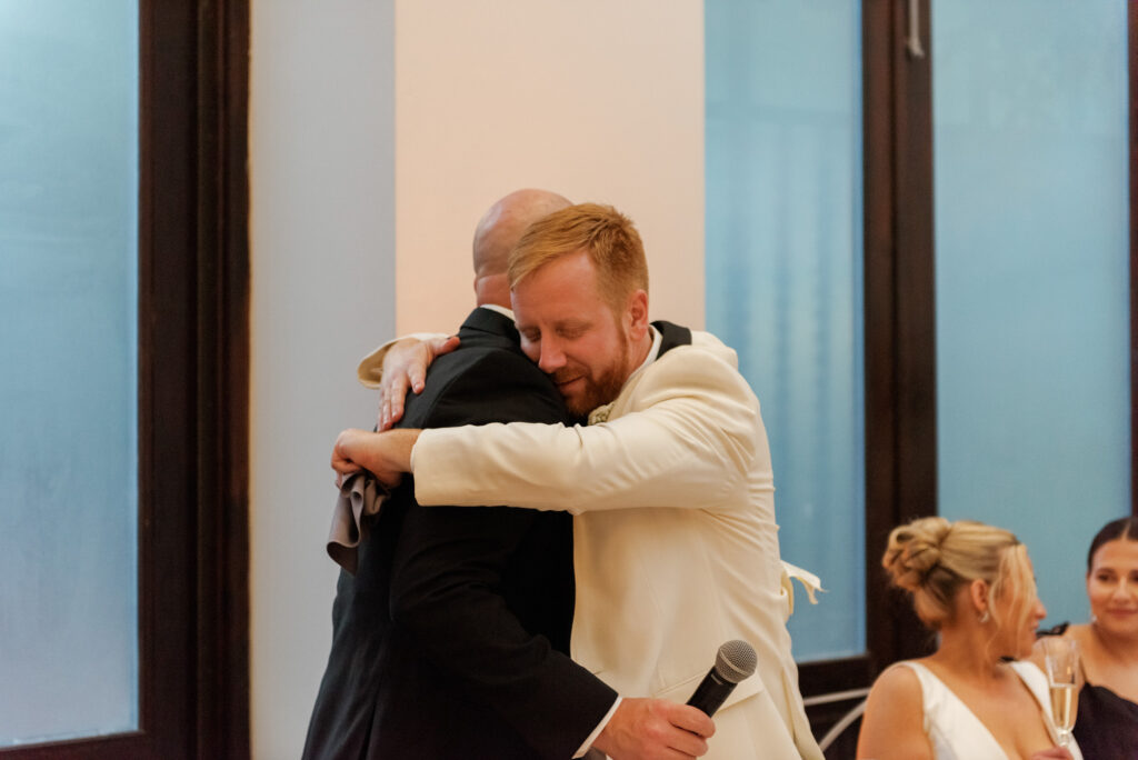 Groom hugging a guest during the reception celebration.
