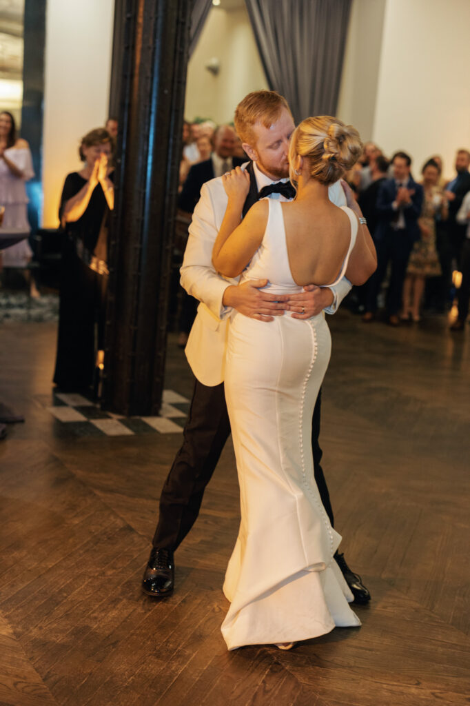 Bride and groom dancing closely together surrounded by guests at Mae District.