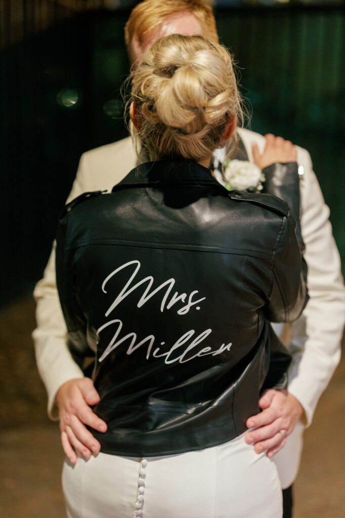 Bride wearing a custom jacket embracing the groom at the end of the night.