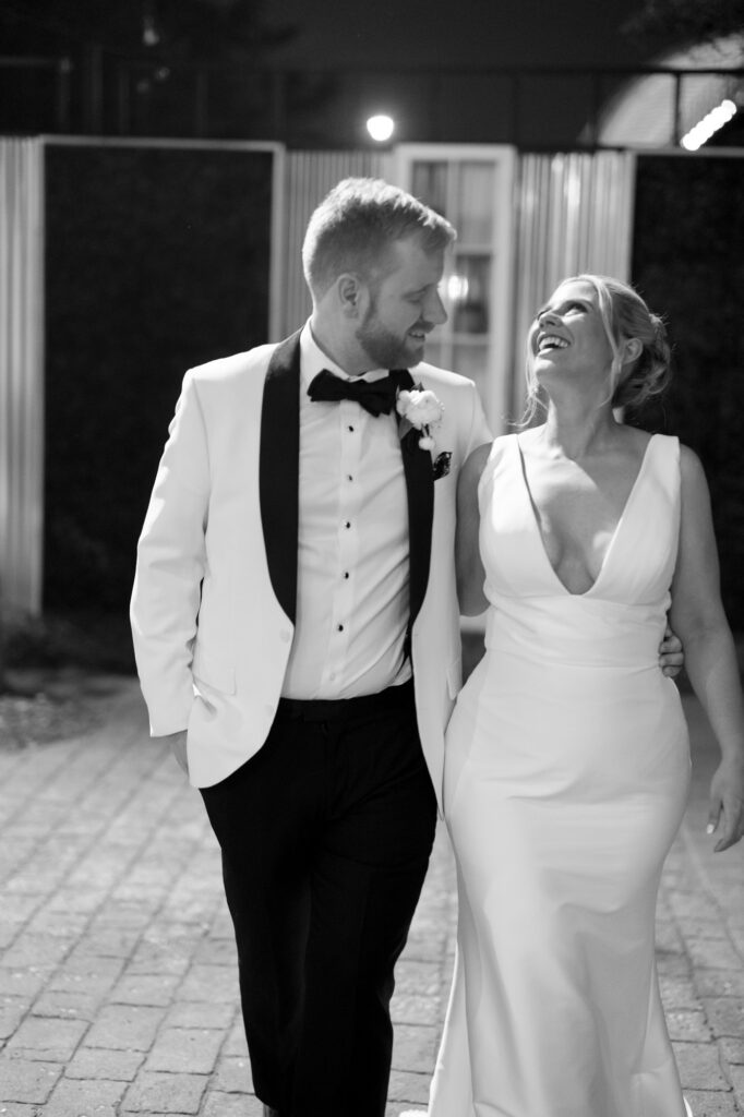 Bride and groom walking together at night holding hands after their reception.