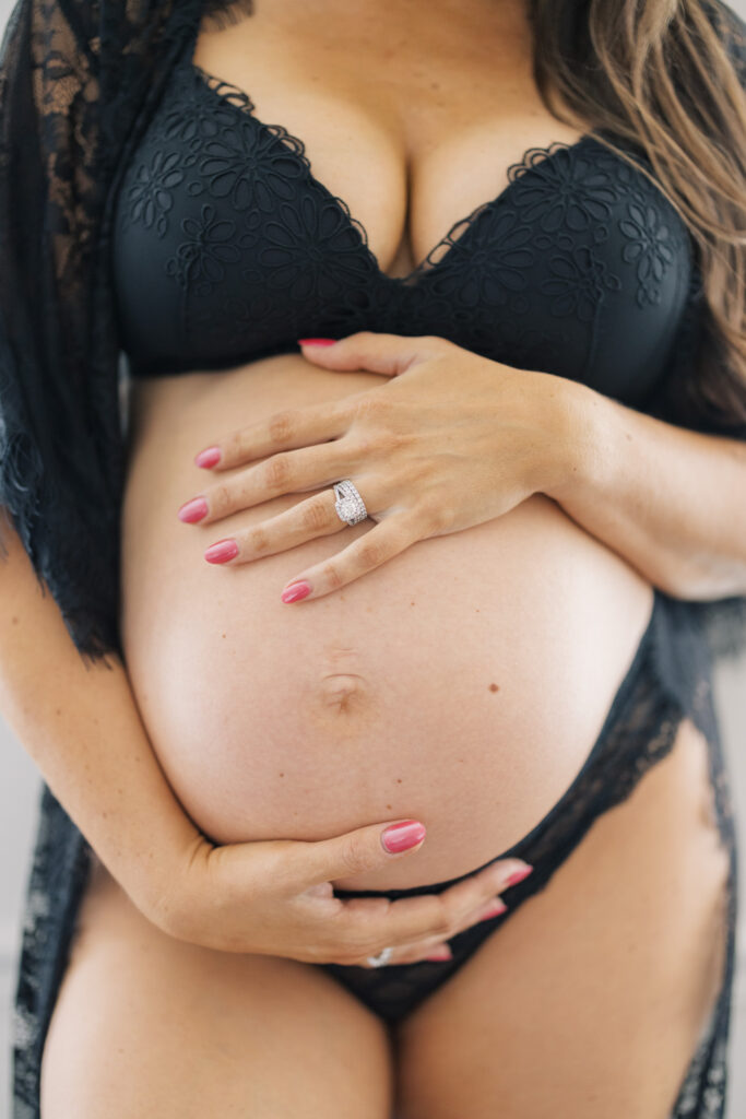 Close up maternity boudoir photo of pregnant belly with hands and engagement ring