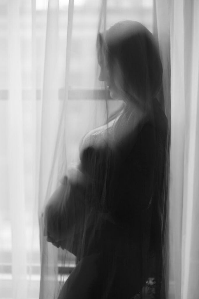 Soft focus maternity silhouette behind curtains in natural light