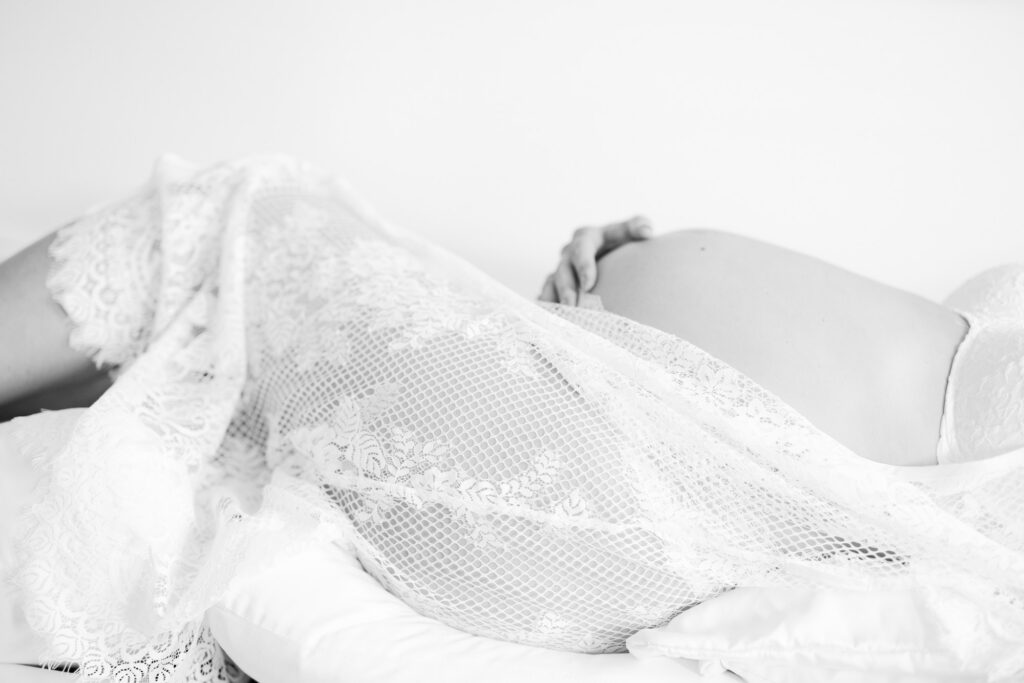 Close up maternity boudoir image of pregnant body covered in lace fabric