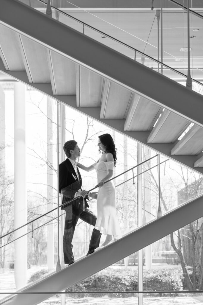 Black and white engagement photo on museum staircase with couple