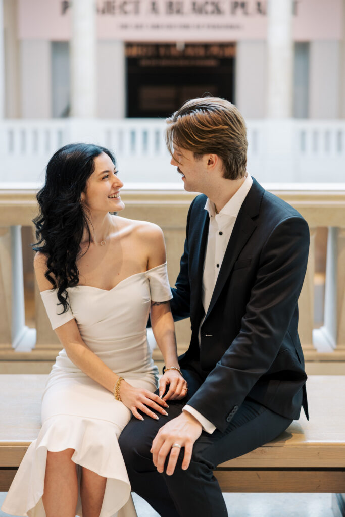 Engagement photo sitting together inside museum with soft natural light