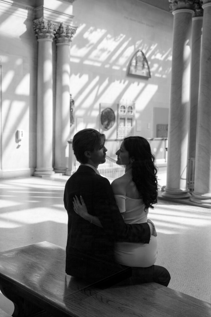 Black and white engagement photo seated couple in Art Institute gallery