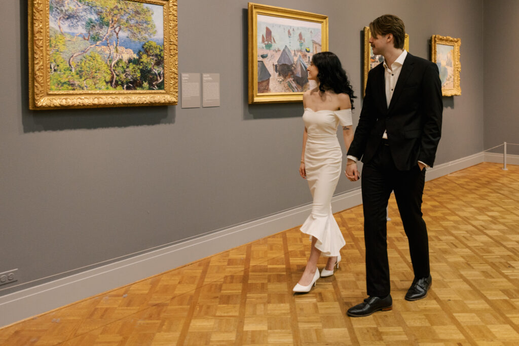 Candid engagement photo inside museum hallway with couple walking