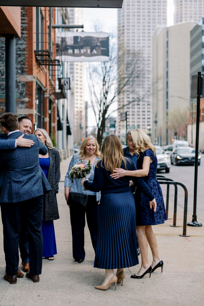 Couple arriving at Sepia in Chicago with family nearby