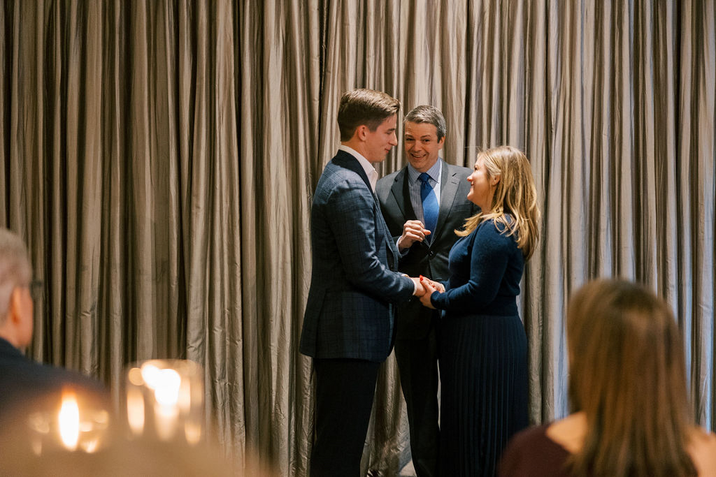 Bride smiling during ceremony with guests in background