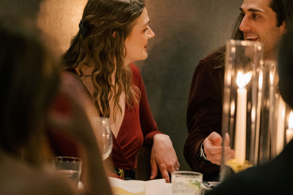 Guests talking and laughing at candlelit dinner table