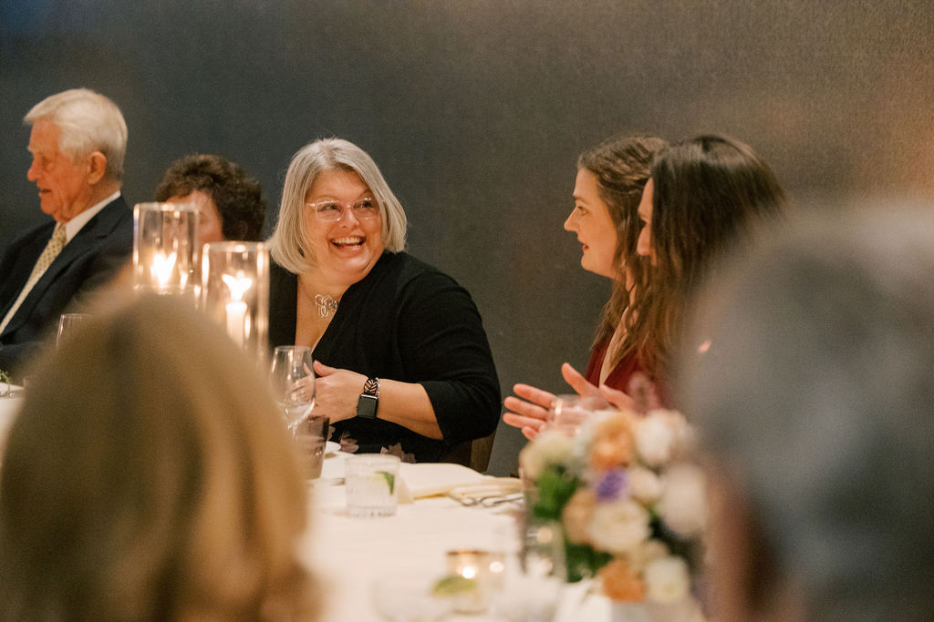 Guests talking and laughing at candlelit dinner table