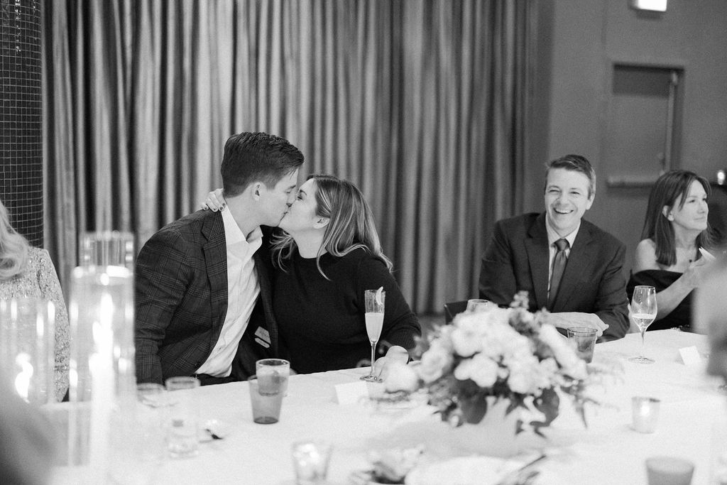 Couple kissing at dinner table with guests nearby at Sepia in Chicago