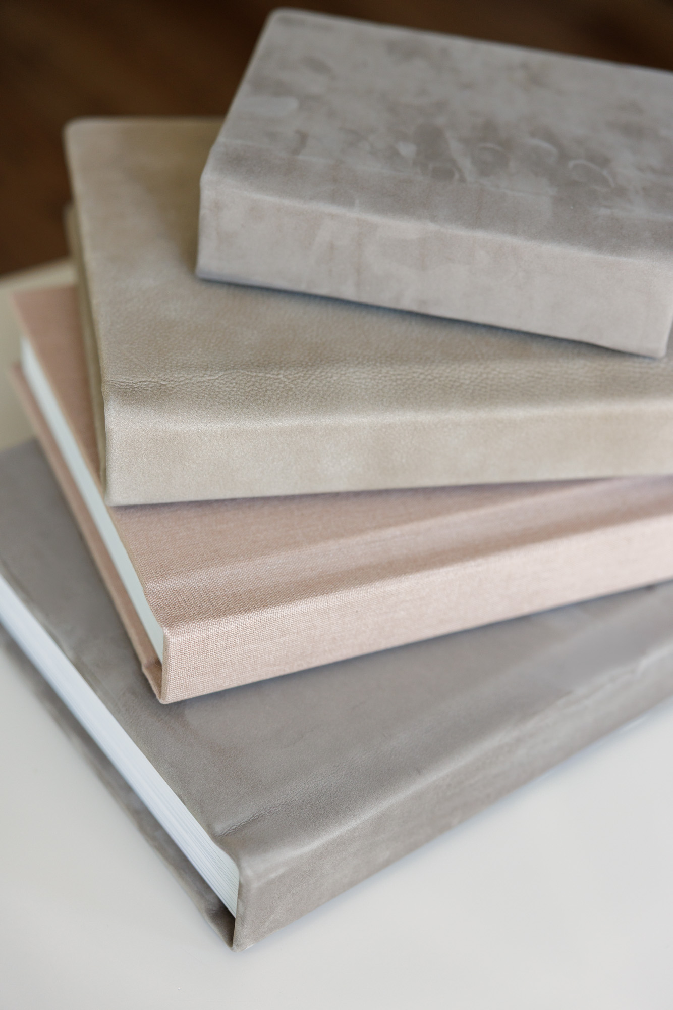 Stacked luxury linen wedding albums in soft neutral tones with fine art texture